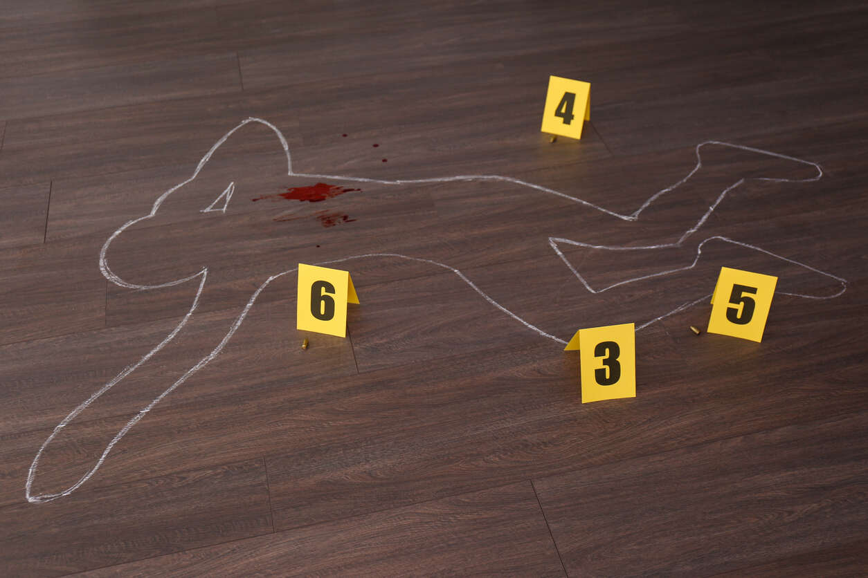 Chalk outline of a body on a wooden floor with bloodstains and crime scene markers, symbolizing an attempted murder investigation.