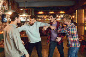 Group of men arguing and fighting in a bar setting, representing a bar fight situation leading to possible aggravated assault charges.